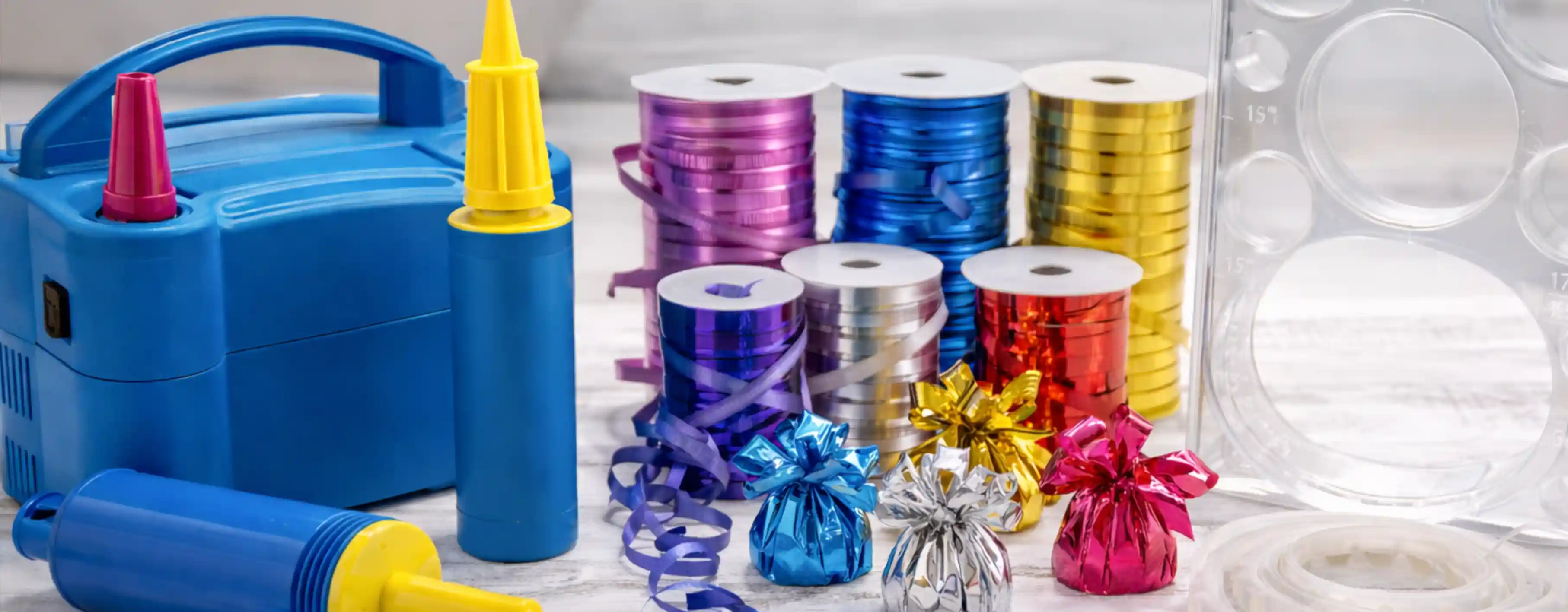 Professional balloon decorating tools including pumps, ribbon, weights, and tape strips