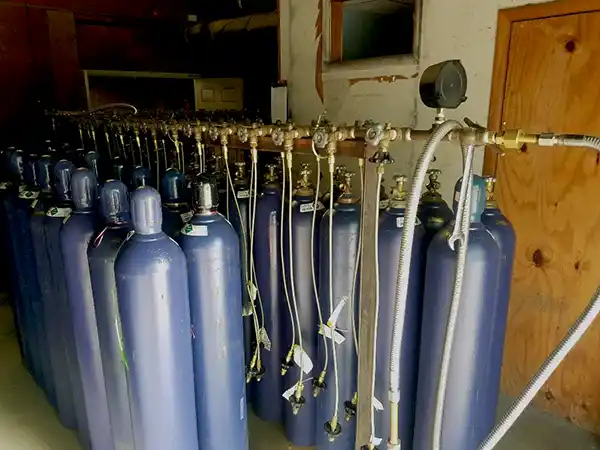 Pictured is helium cylinders lined up in a store room, ready for delivery to customers. Helium tank rental and delivery for your next event in Jonesboro and near Jonesboro.